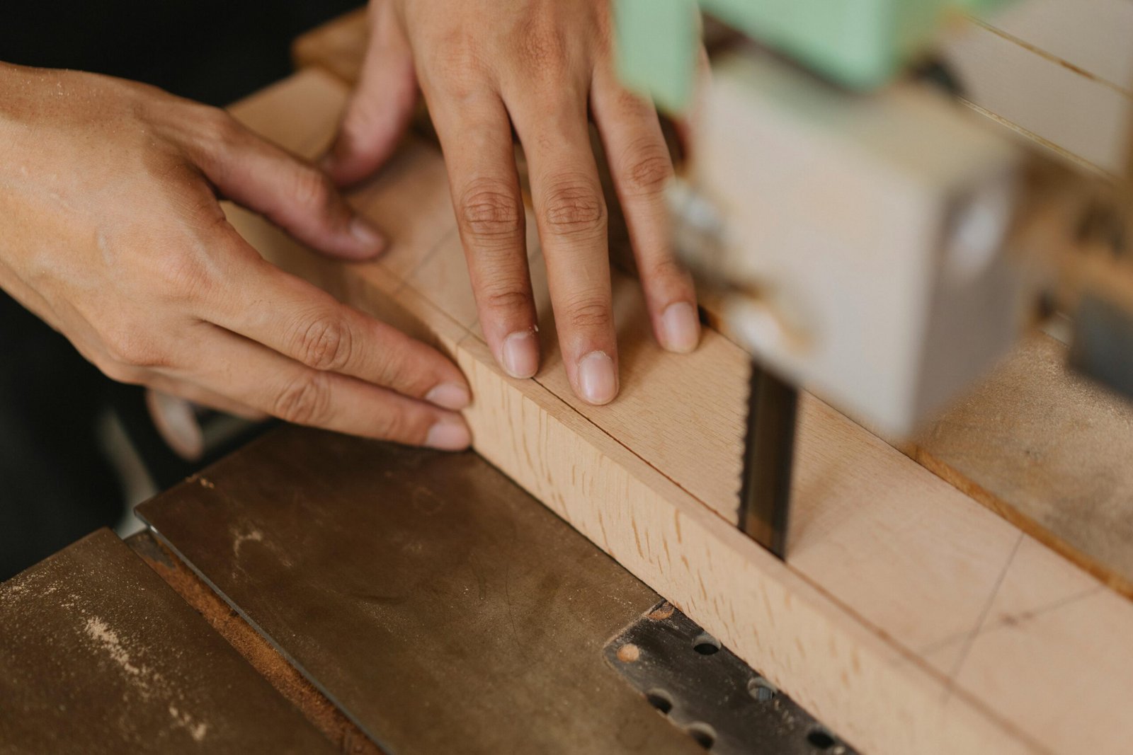 From above of crop anonymous woodworker sawing lumber using band saw with sharp blade in workshop