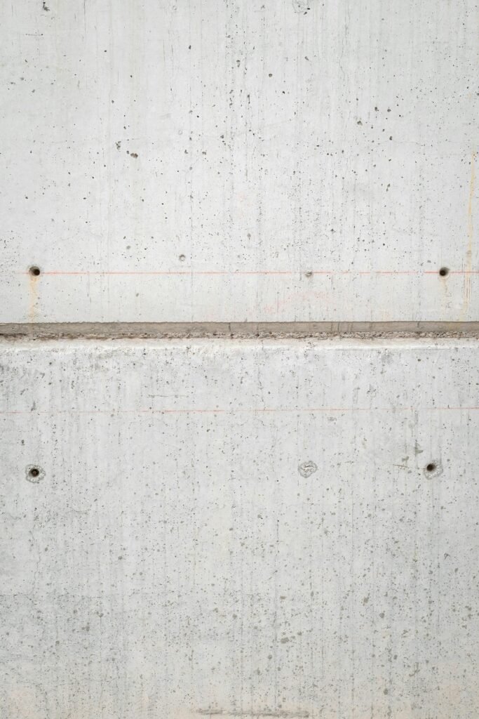 A close-up of a textured concrete wall with visible holes and linear patterns, ideal for backgrounds.