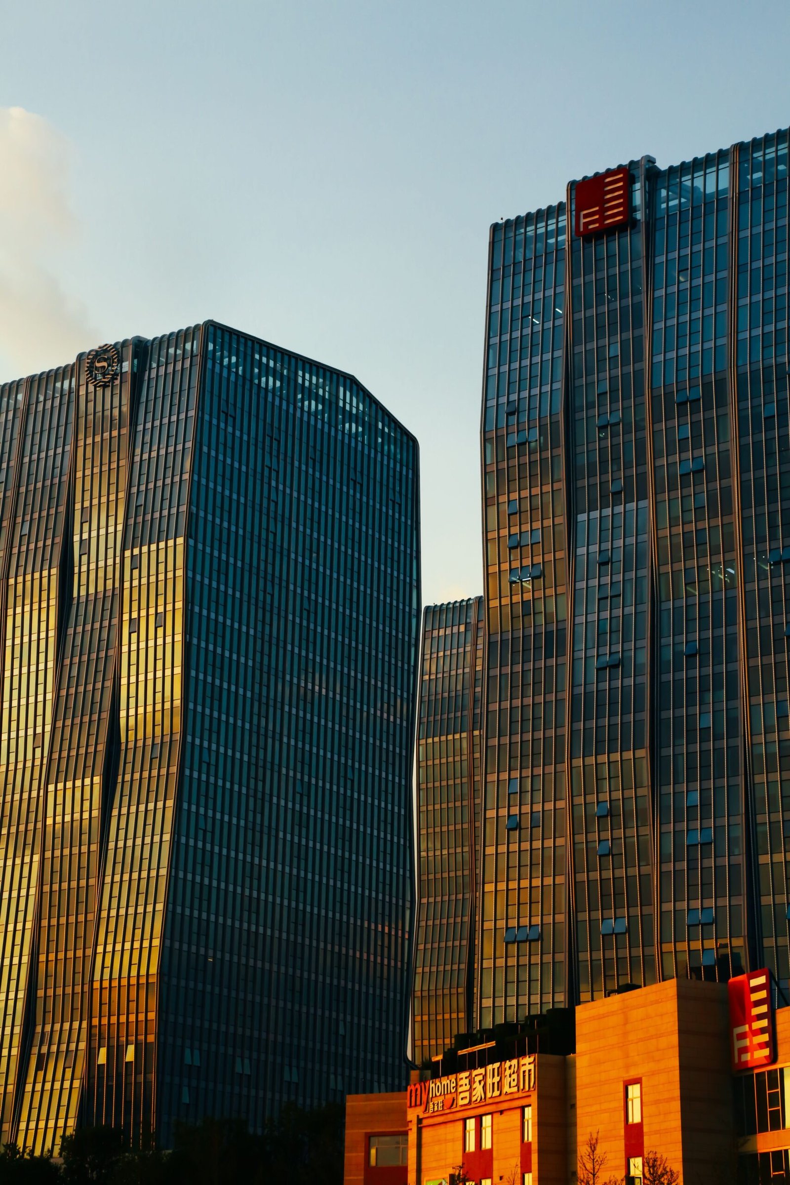 Tall modern skyscrapers reflecting sunset light in the city skyline.
